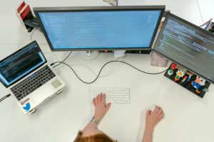 pexels-photo-3861972-3861972 A female software engineer coding on dual monitors and a laptop in an office setting.
