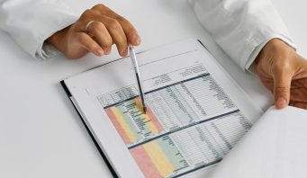 Doctor hands examining and pointing at medical charts in a close-up view.